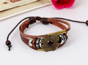Macro detail of multi-layer leather bracelet with bronze flower charm and wooden beads