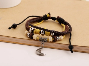 Close-up of multilayer braided leather bracelet with vintage metal moon and star charms