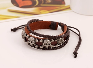Dettaglio del bracciale multistrato in pelle intrecciata con ciondoli a teschio vintage