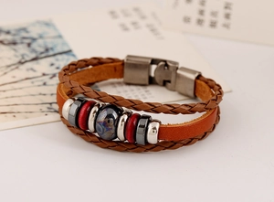 Detail of multi-layer braided brown leather bracelet with metal beads and stone charm