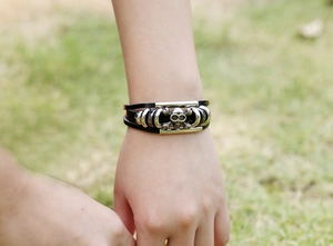 Dettaglio del bracciale multistrato in pelle con teschio e ossa incrociate argento