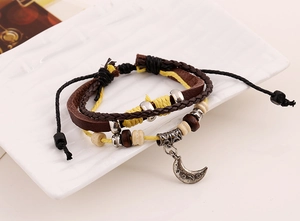 Detail of multilayer leather bracelet featuring a vintage silver moon charm with beads