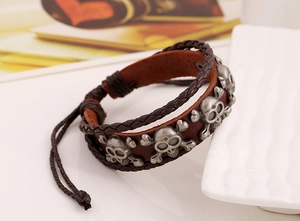 Dettaglio macro del bracciale multistrato in pelle intrecciata con teschi in lega