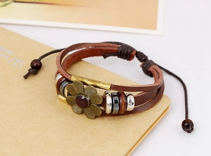 Detail view of woven leather bracelet featuring a bronze alloy flower and adjustable cord