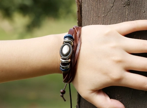Dettaglio di un bracciale in pelle intrecciata multistrato con perline di legno e metallo