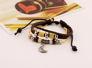 Detail of bohemian layered leather bracelet featuring moon pendant and wooden beads