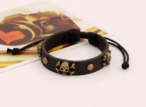 Détail du bracelet punk en cuir avec rivets tête de mort en bronze et cordon tressé réglable