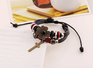 Macro detail of multilayer leather bracelet with bronze flower and cross charms