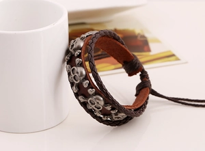 Dettaglio del bracciale in pelle intrecciata con teschi in lega vintage e chiusura regolabile