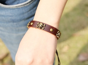 Détail d'un bracelet punk en cuir marron avec des clous tête de mort au poignet