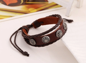 Detail of vintage dark brown braided leather bracelet with silver floral metal charms