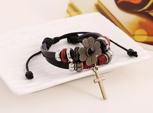Detail of multilayer leather bracelet with bronze flower, cross charms and beads