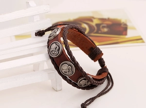 Detail eines mehrlagigen Lederarmbands mit silbernen Totenkopf-Anhängern im Retro-Stil