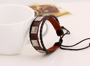Detail of a punk leather bracelet with silver pyramid studs on a white porcelain cup