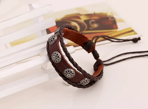 Detail of vintage braided leather bracelet featuring hollowed metal charms and slider knot