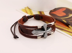 Detail of vintage brown double-layer leather bracelet with wide silver cross and adjustable cord