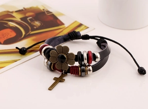 Detail view of multi-layer leather bracelet with bronze flower and cross charms