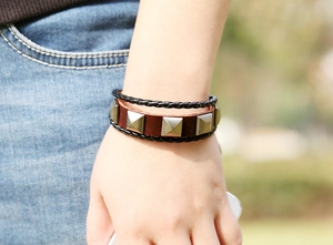 Detail of multilayer leather bracelet featuring square metal studs on a brown strap
