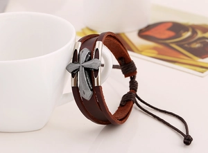 Detail of multi-layer leather bracelet featuring an antique metal cross and drawstrings