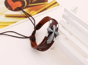 Macro shot of brown multi-layer leather bracelet with vintage cross and metal details