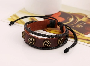 Détail d'un bracelet en cuir marron foncé avec breloques roses bronzes et cordon tressé
