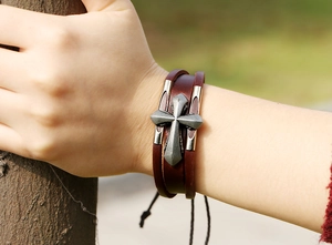 Close-up of vintage brown multilayer leather bracelet with metal cross on male wrist