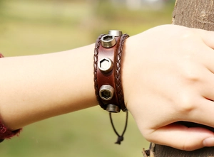 Detail of vintage brown leather bracelet with industrial metal nuts on wrist