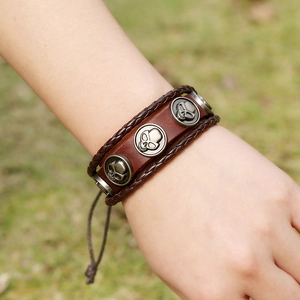 Braunes Lederarmband mit silbernen Totenkopf-Anhängern aus Metall am Handgelenk
