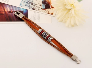 Detail of multi-layer braided leather bracelet with central bead and metal clasp