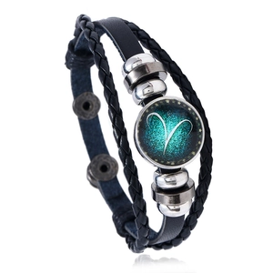 Detail of Aries zodiac sign in glass charm on multilayered black leather bracelet
