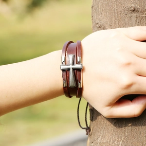 Bracciale multistrato in pelle vintage con ciondolo a croce sul polso di una modella