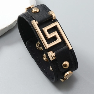 Detail view of black punk leather bracelet with gold geometric buckle and rivets
