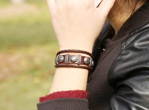 Close-up of multilayer braided leather bracelet with vintage alloy charms on wrist