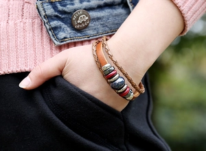 Close-up of layered leather bracelet with ceramic beads on model's wrist outdoors