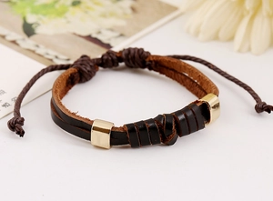 Détail d'un bracelet en cuir tressé avec ornements dorés et cordon de serrage réglable