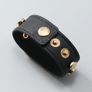 Detail of black wide leather bracelet with four gold stud snap buttons and lychee texture