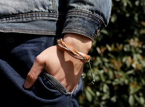 Close-up of a handmade braided leather bracelet worn on a wrist in a natural outdoor setting