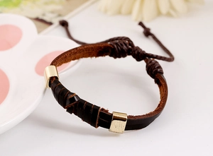 Détail du bracelet en cuir tressé vintage avec curseurs dorés et cordon réglable