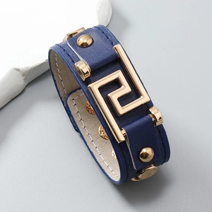 Detail of blue leather punk bracelet with gold Greek Key motif and polished metal studs