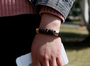 Détail d'un bracelet en cuir noir tressé avec des accents métalliques dorés
