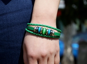 Detail of multi-layer green leather bracelet with cat eye stone and beads on wrist