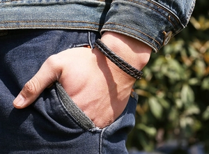 Detail of double-layer black braided leather bracelet on male model's wrist