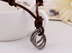 Gros plan du pendentif à triple anneau en alliage sur un collier en cuir marron vintage