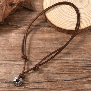 Macro shot of retro hammered silver ring pendant on braided brown leather necklace
