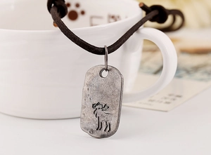Macro shot of an antique silver elk pendant hanging on a ceramic cup edge