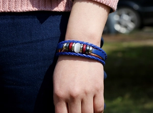 Detail of blue multilayer braided leather bracelet with white cat eye stone on wrist
