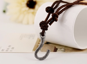 Macro shot of a vintage silver fish hook pendant with a dark brown leather cord necklace