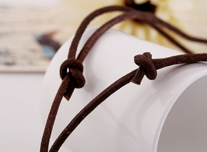 Vue macro d'un cordon en daim marron foncé avec nœuds faits main pour collier rétro