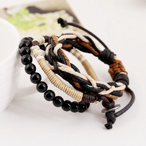Close-up of bohemian layered bracelets set with black beads and handmade braided cords