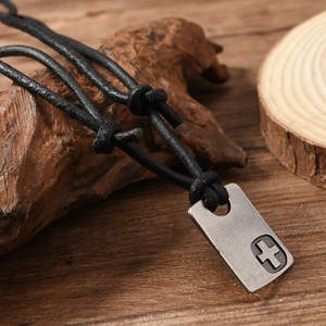 Retro cross pendant necklace for men with black leather cord on rustic wood background